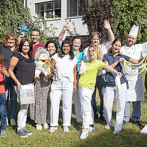 Gruppenfoto mehrerer Mitarbeiter und Mitarbeiterinnen im Garten des Seniorenwohnhauses Liefering