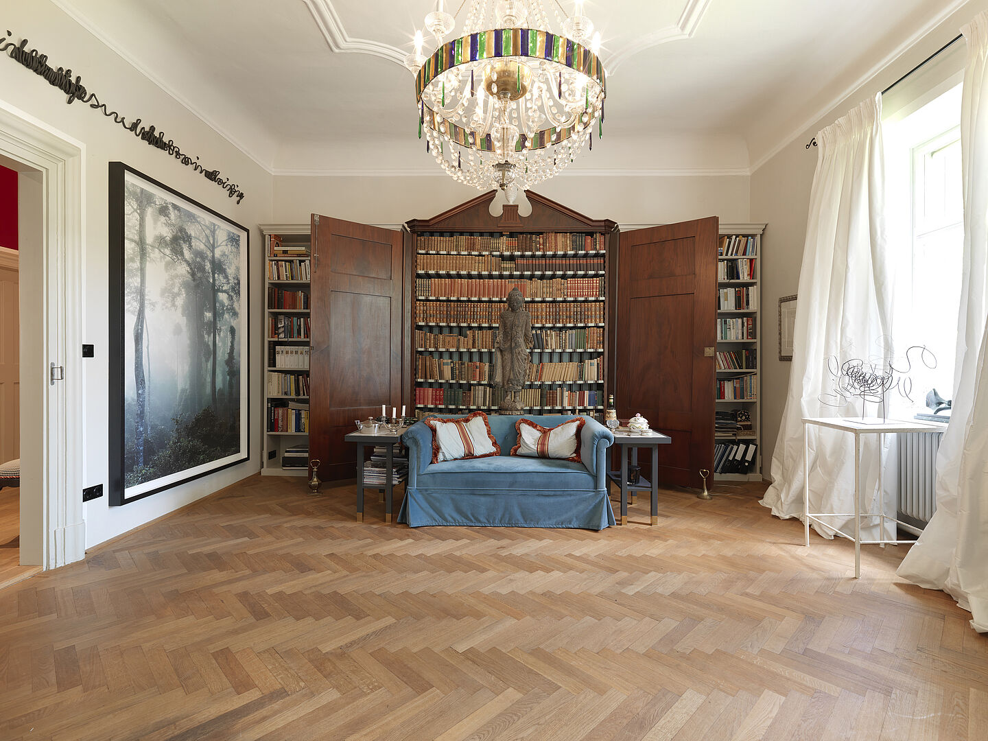 Bild - Like Home Foto eines Zimmers mit blauer Couch vor eine Bücherwand