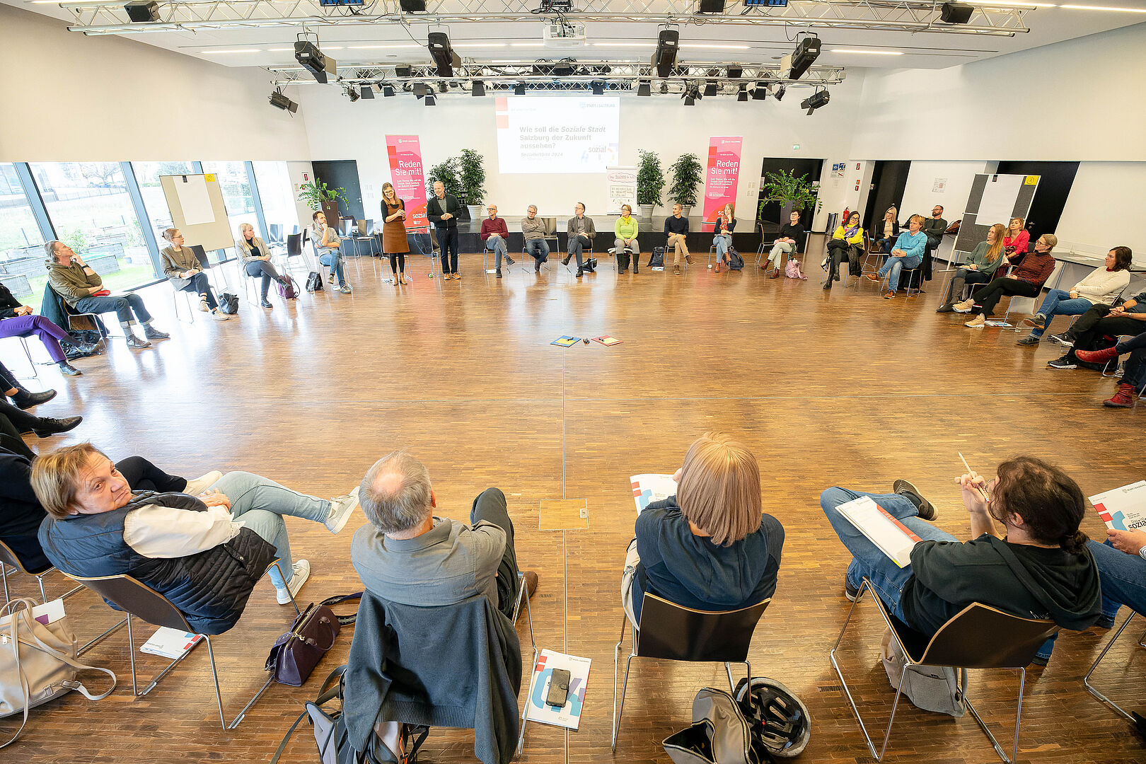 40 Personen sitzen in einem Sessekreis und besprechen ihre Ideen zum neuen Sozialleitbild der Stadt Salzburg.