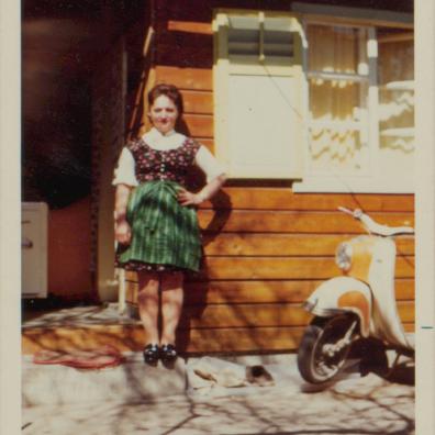 Frau im Dirndl vor einem Haus